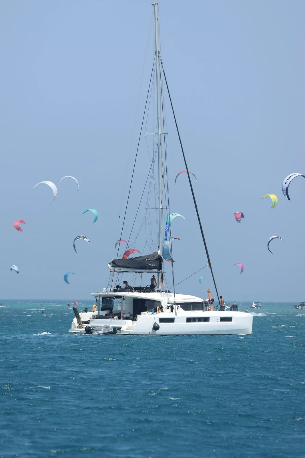 Catamaran at anchor surrounded by kites in a bay