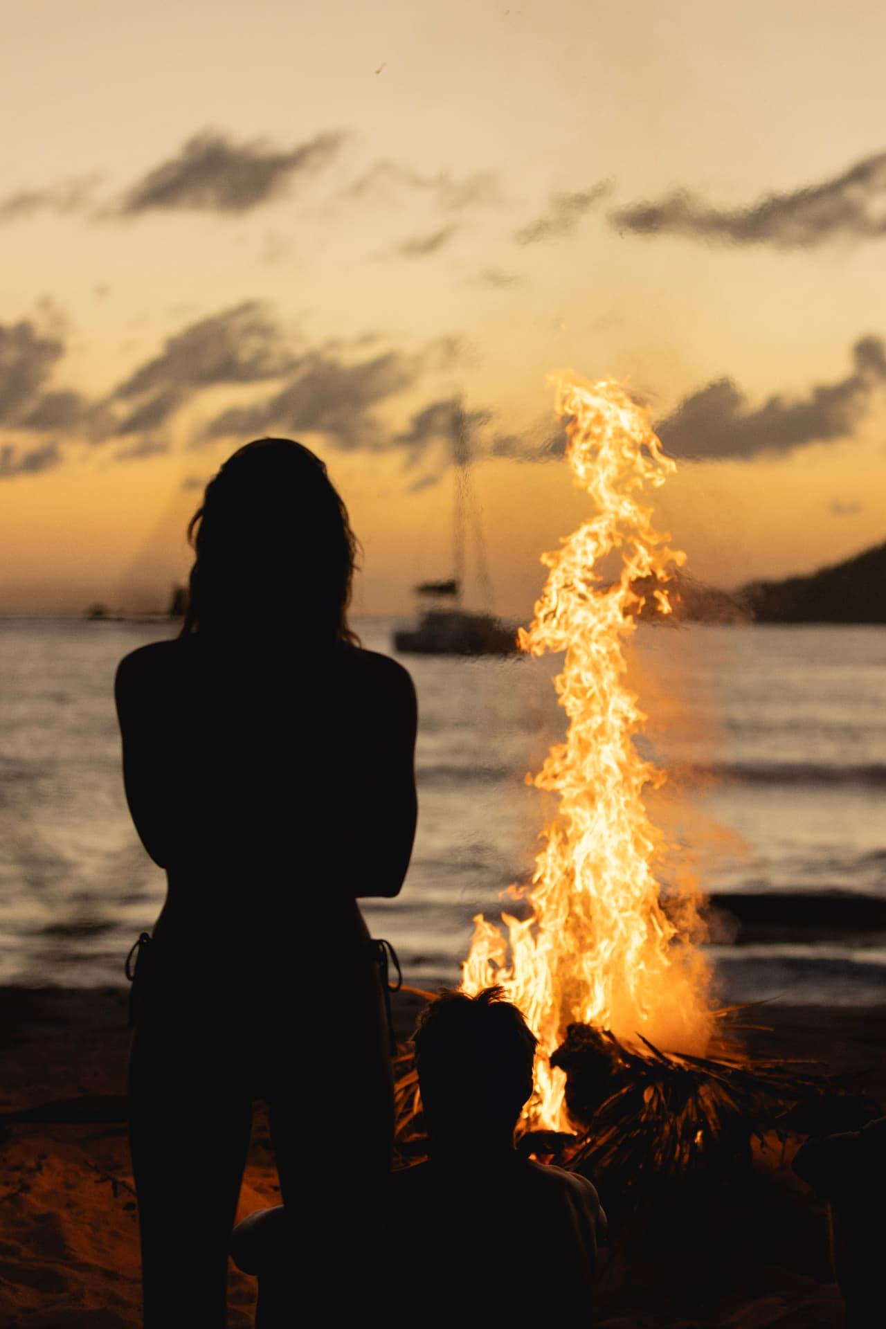 The crew gathering around a beach fire at sunset