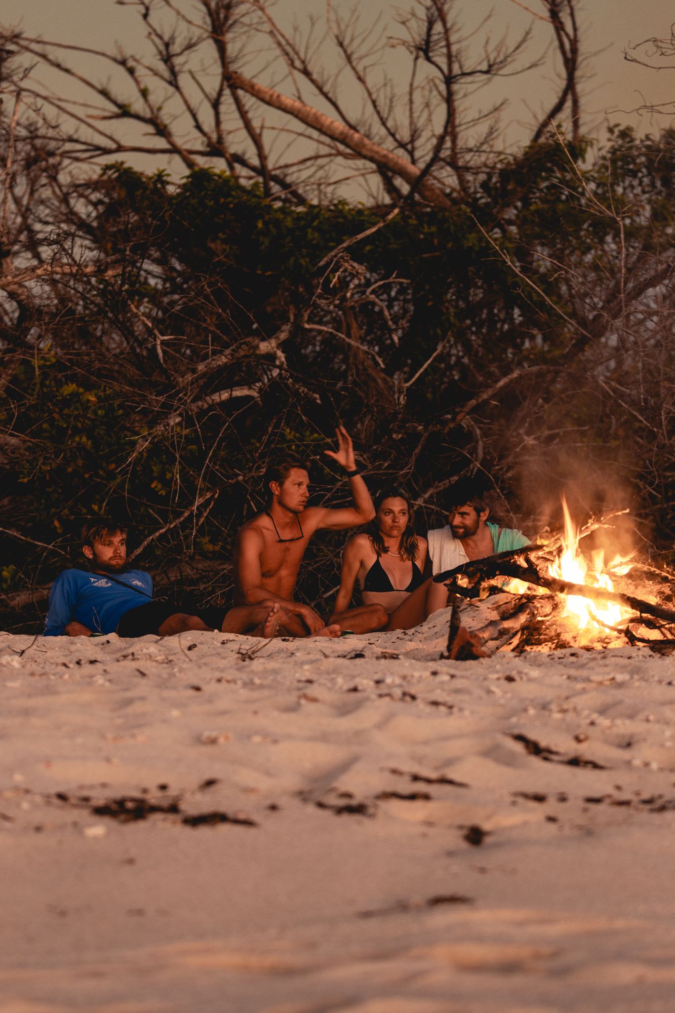 The crew around a fire on the beach at dusk