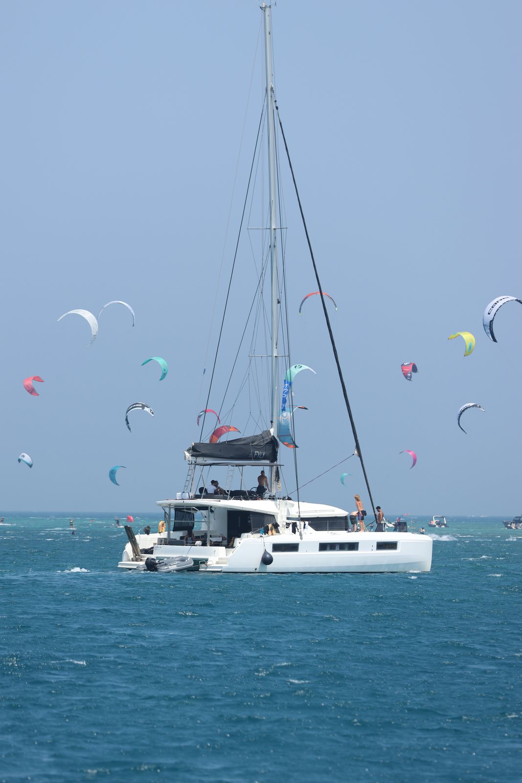 Catamaran at anchor surrounded by kites in the bay