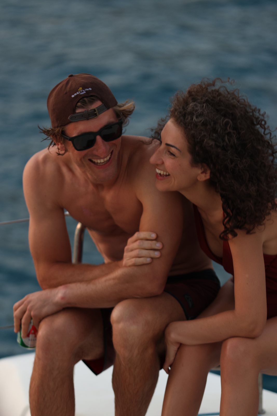 Two guests laughing together on deck at dusk