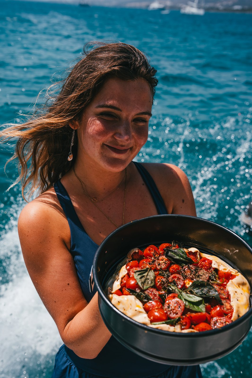 Chef carrying a fresh tomato tart across the deck