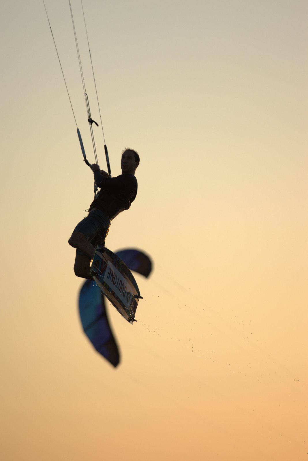 Kitesurfer mid-jump against a sunset sky