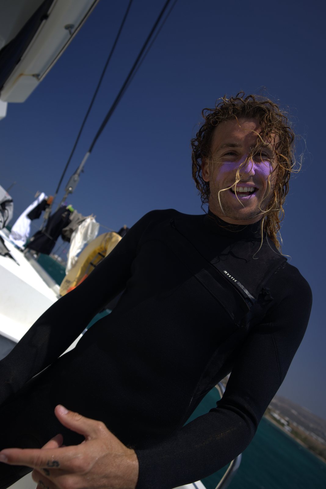 Guest in a wetsuit laughing on deck with zinc on his face