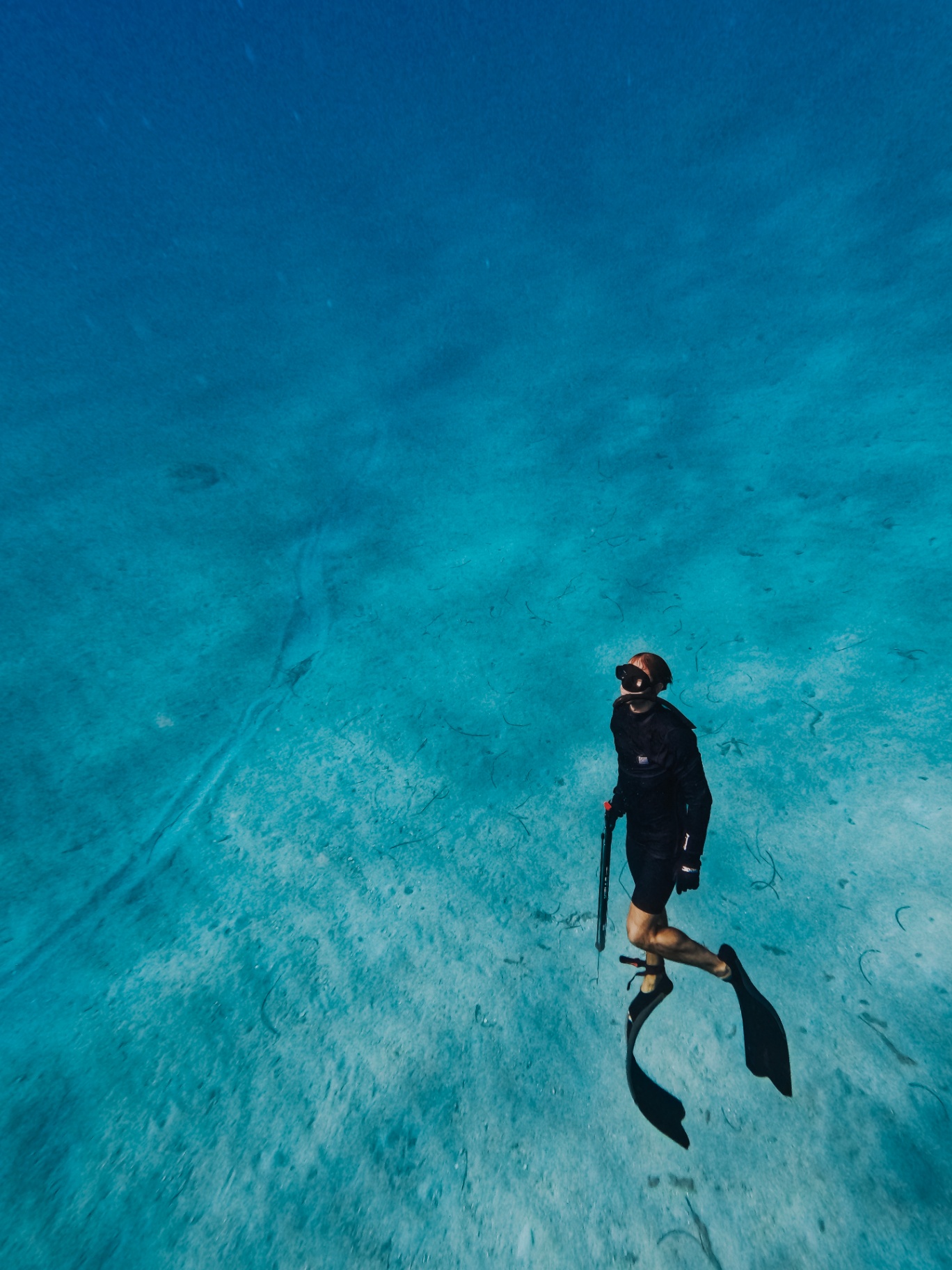 Freediver gliding over white sand