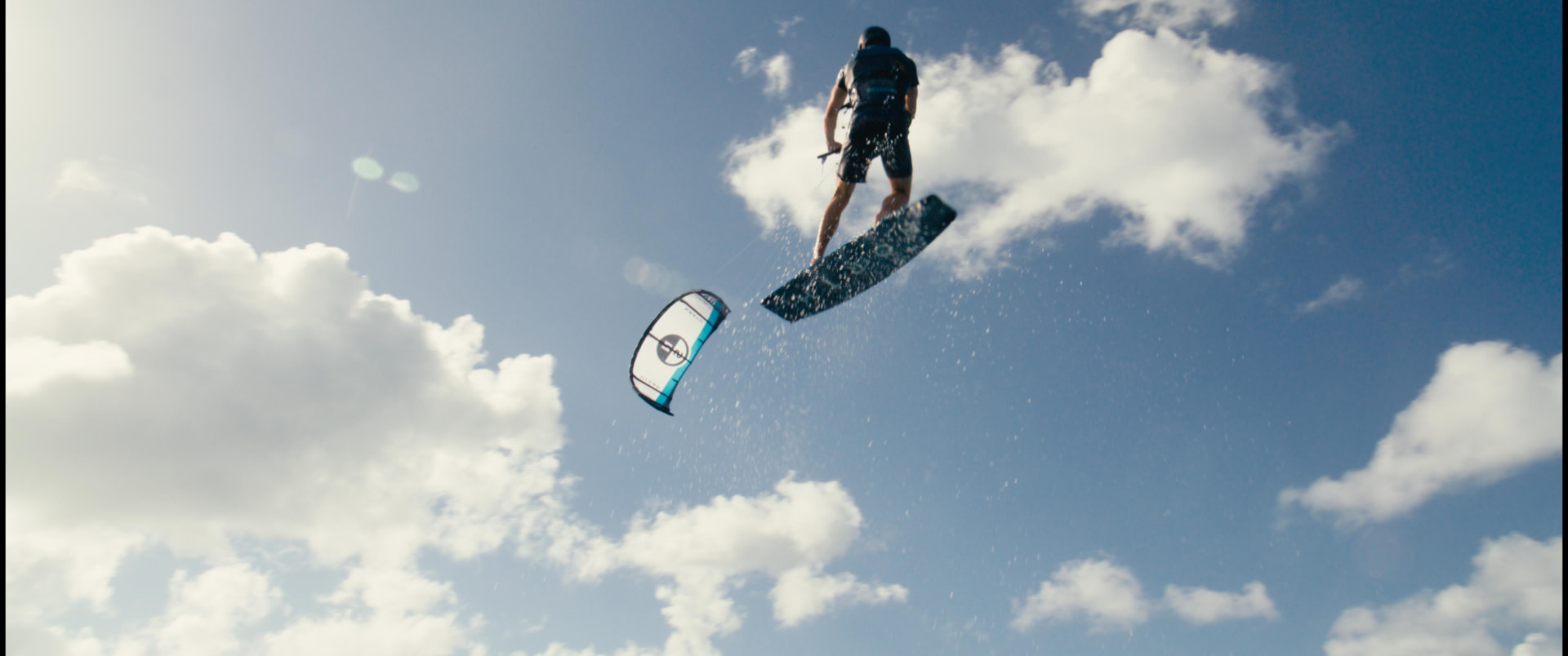 Rider mid-air against the clouds, kite below