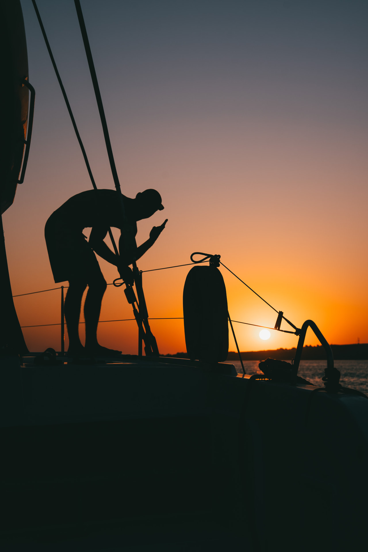 Crew member silhouetted on the bow at sunset